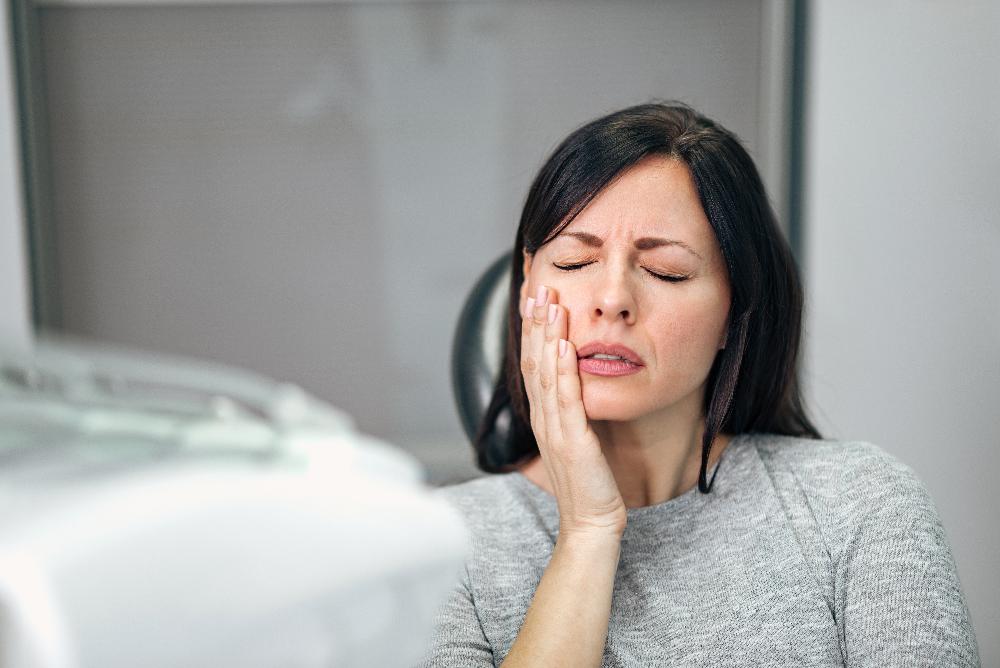 woman holding jaw from infected tooth pain