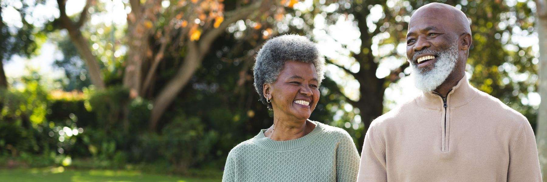 older man and woman smiling while walking in a havertown park